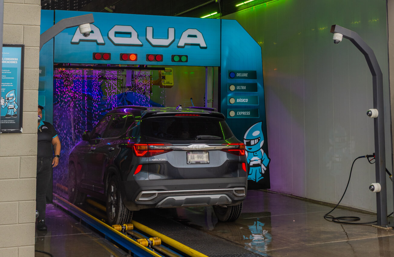 Automóvil gris ingresando a arco de lavado de Aqua Car